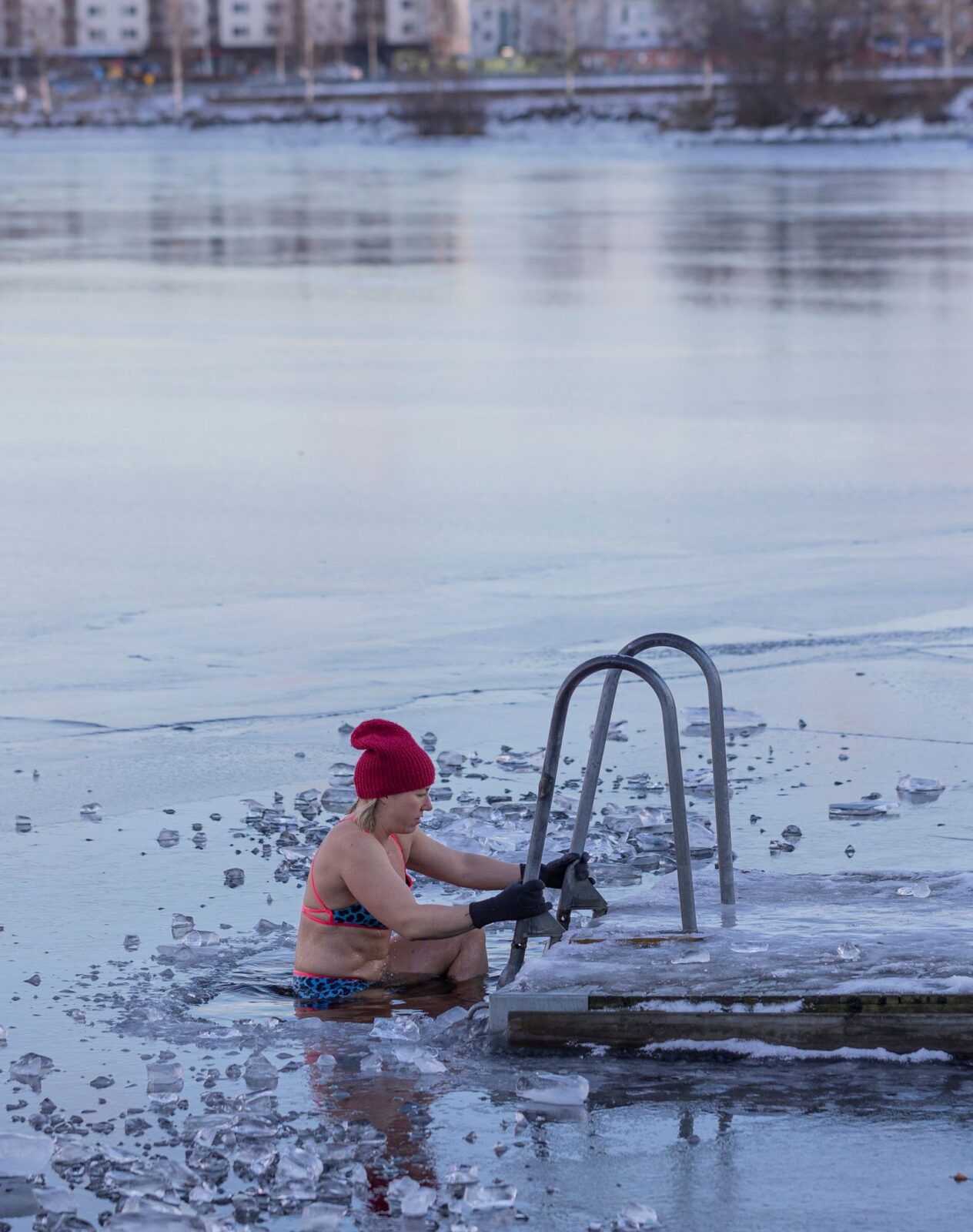 Person descending a ladder into a frozen lake for cold water immersion