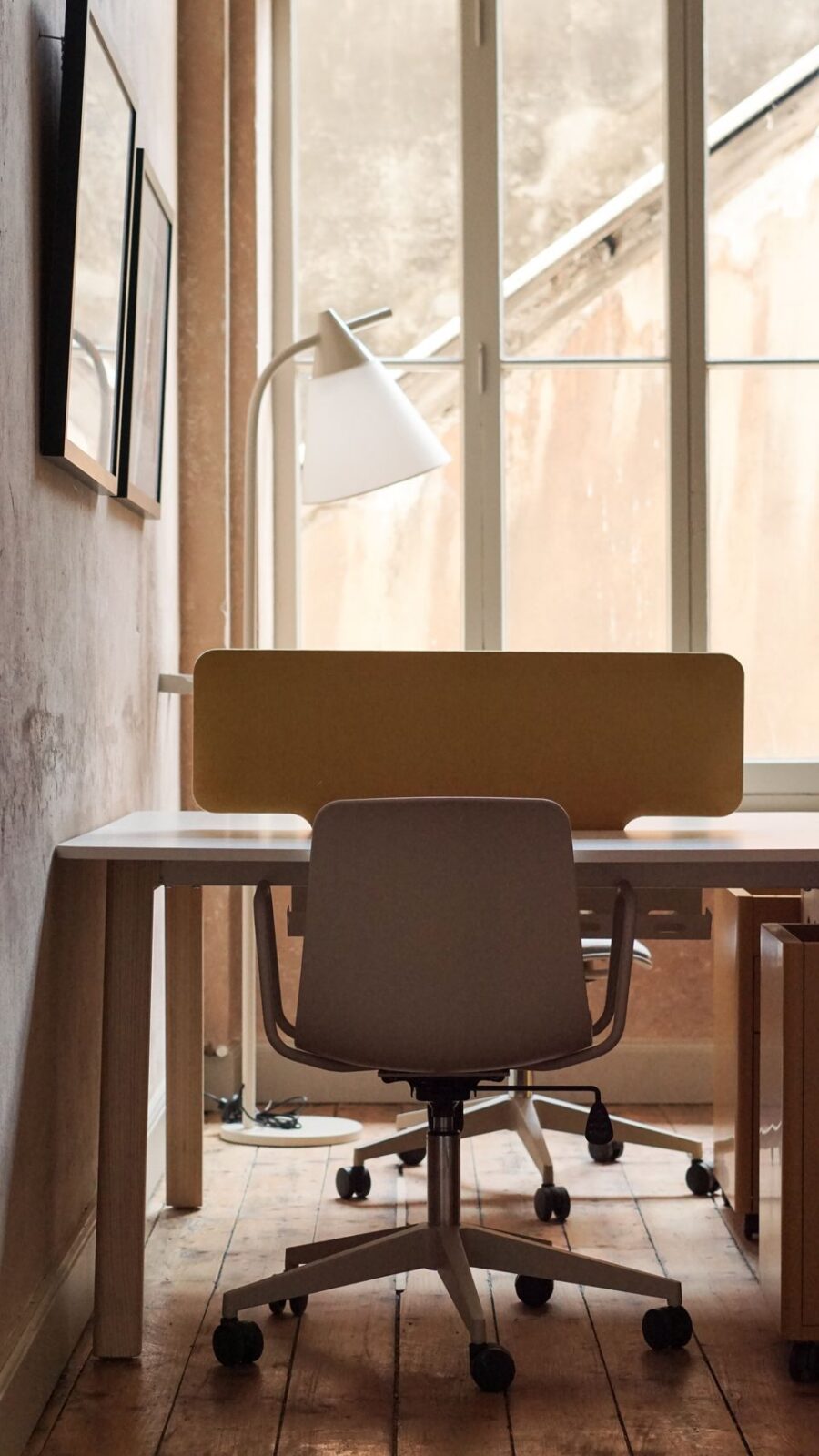 Bright desk lamp beside a window in a softly lit home office