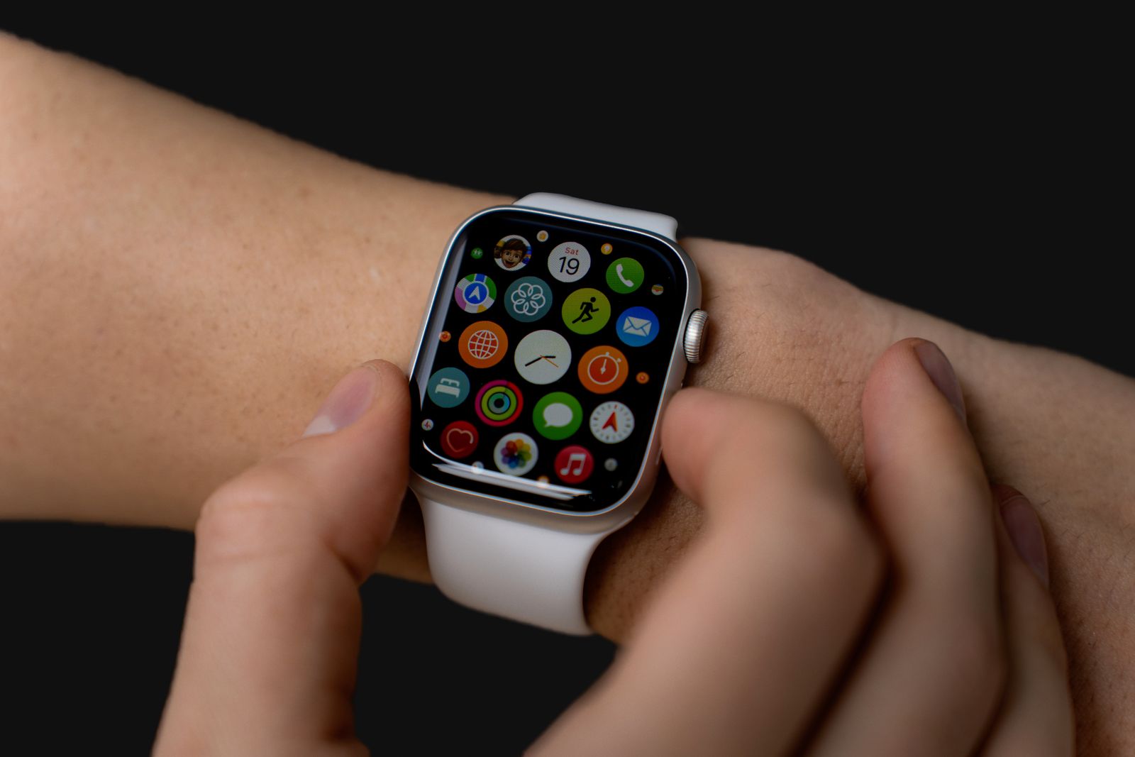 Close-up of a person interacting with a smartwatch displaying apps on a dark background