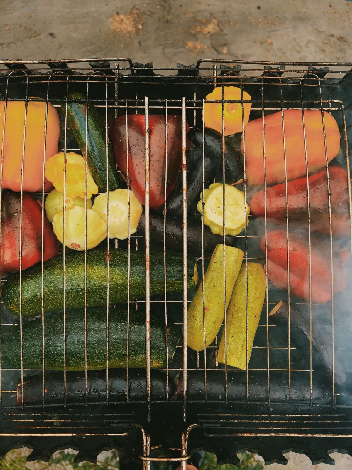 Assorted vegetables grilling on a wire grate over a barbecue