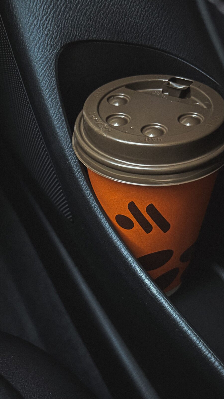 A to-go coffee cup sitting in a car's cup holder