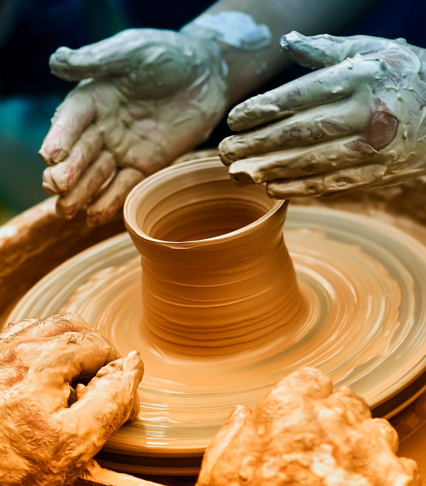 Close-up of hands centering and shaping wet clay on a spinning pottery wheel