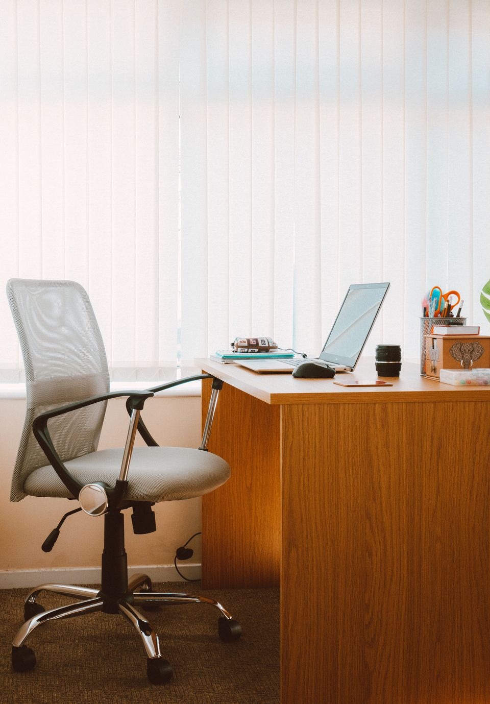 Light-colored office chair at a wooden desk in a naturally lit workspace
