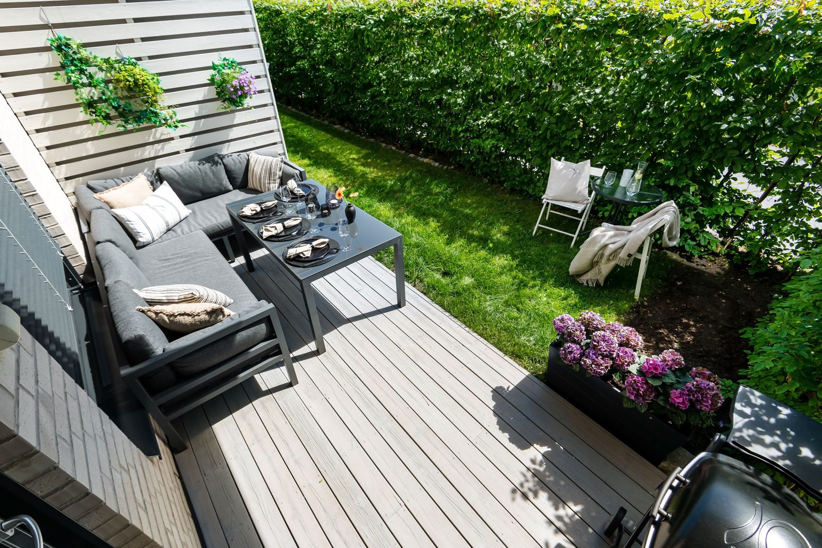 Stylish outdoor patio furniture and greenery arranged on a sunny deck