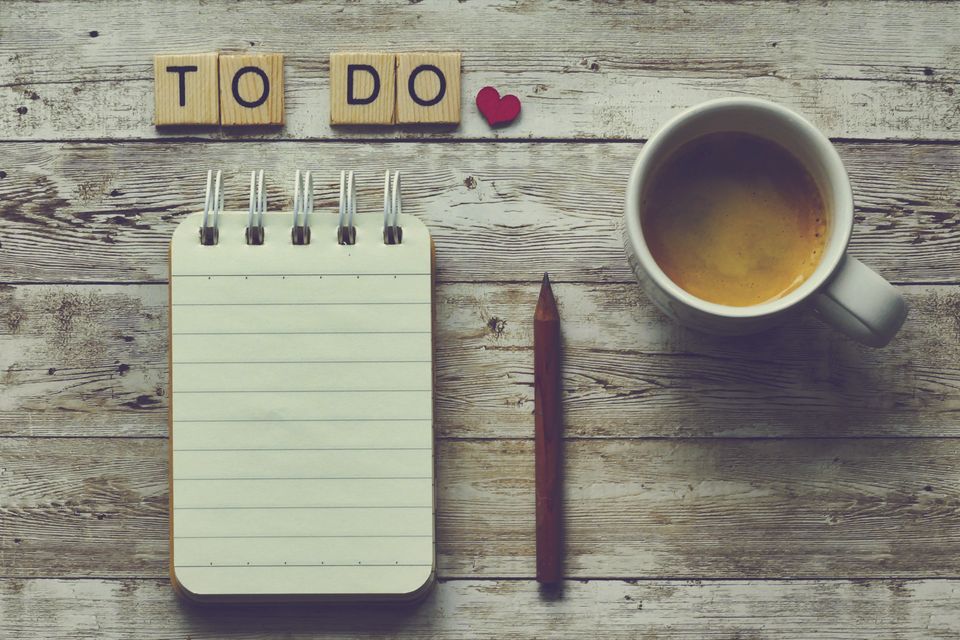 Flat lay of an open lined notebook, a pencil, a coffee cup, and wooden letter tiles on a table