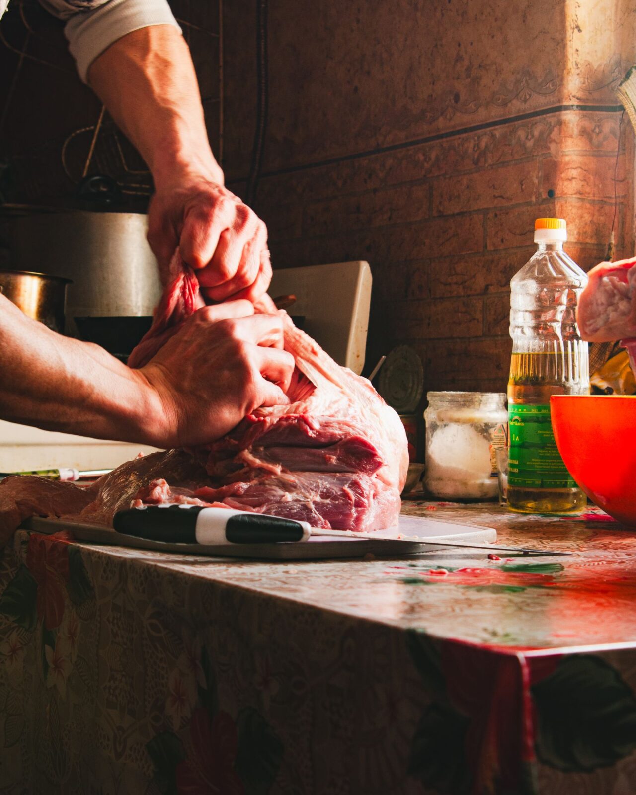 A person preparing a large cut of meat on a kitchen counter ahead of freezing