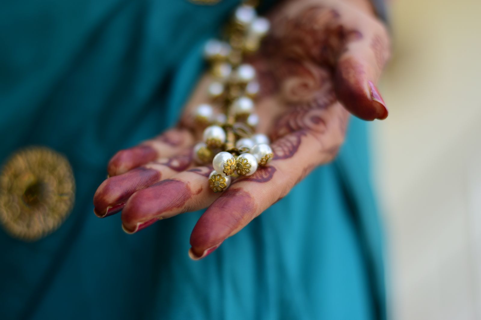 A person's hand holding up a piece of jewelry to inspect it closely