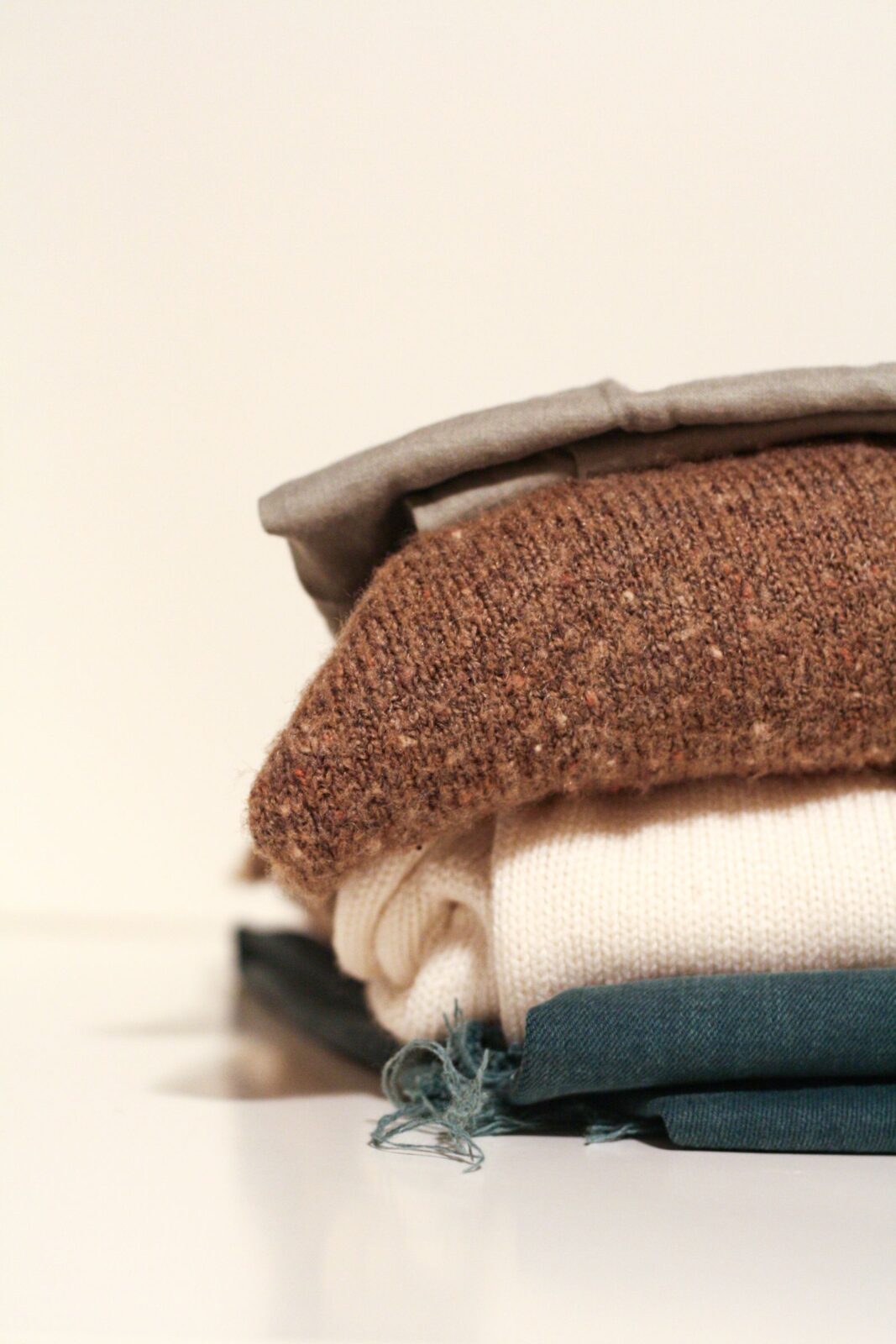 Stack of folded wool and knit sweaters on a white surface