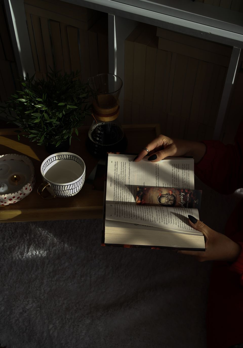 Open book beside a steaming cup of tea in a softly lit, cozy reading corner