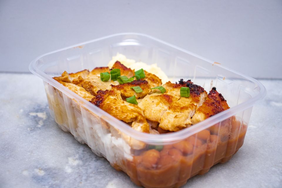 Grilled chicken with rice and beans portioned into a clear meal-prep container
