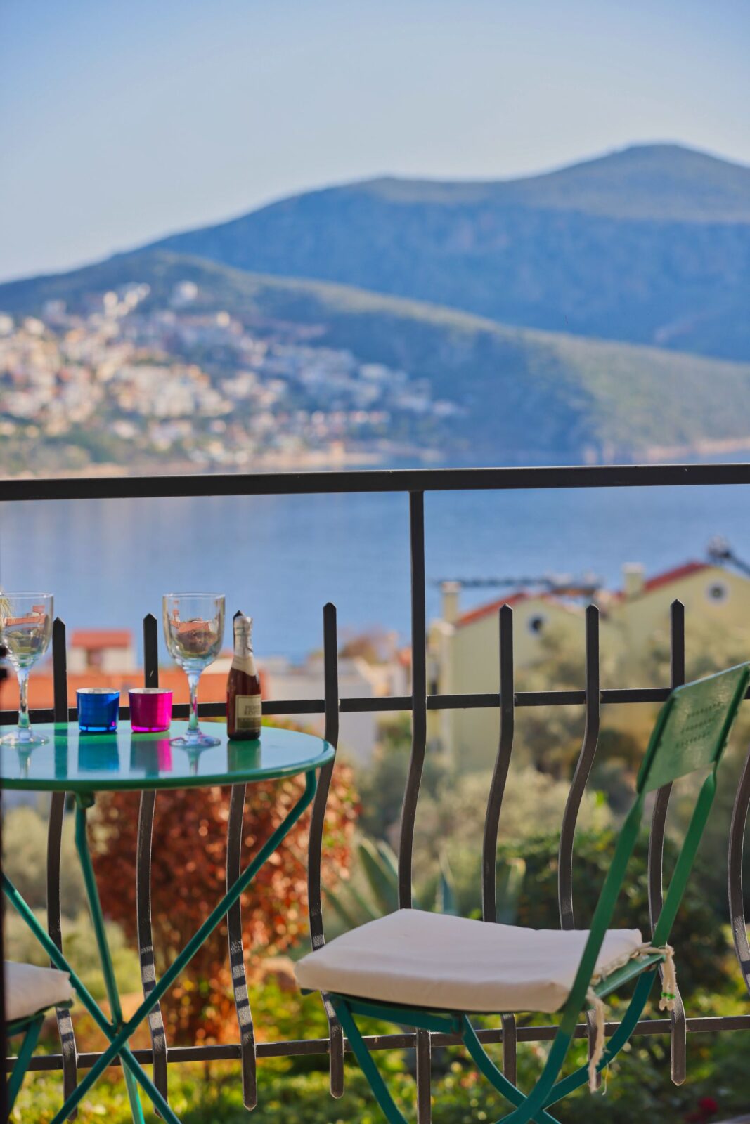 Small table set for two on a narrow balcony overlooking water and mountains