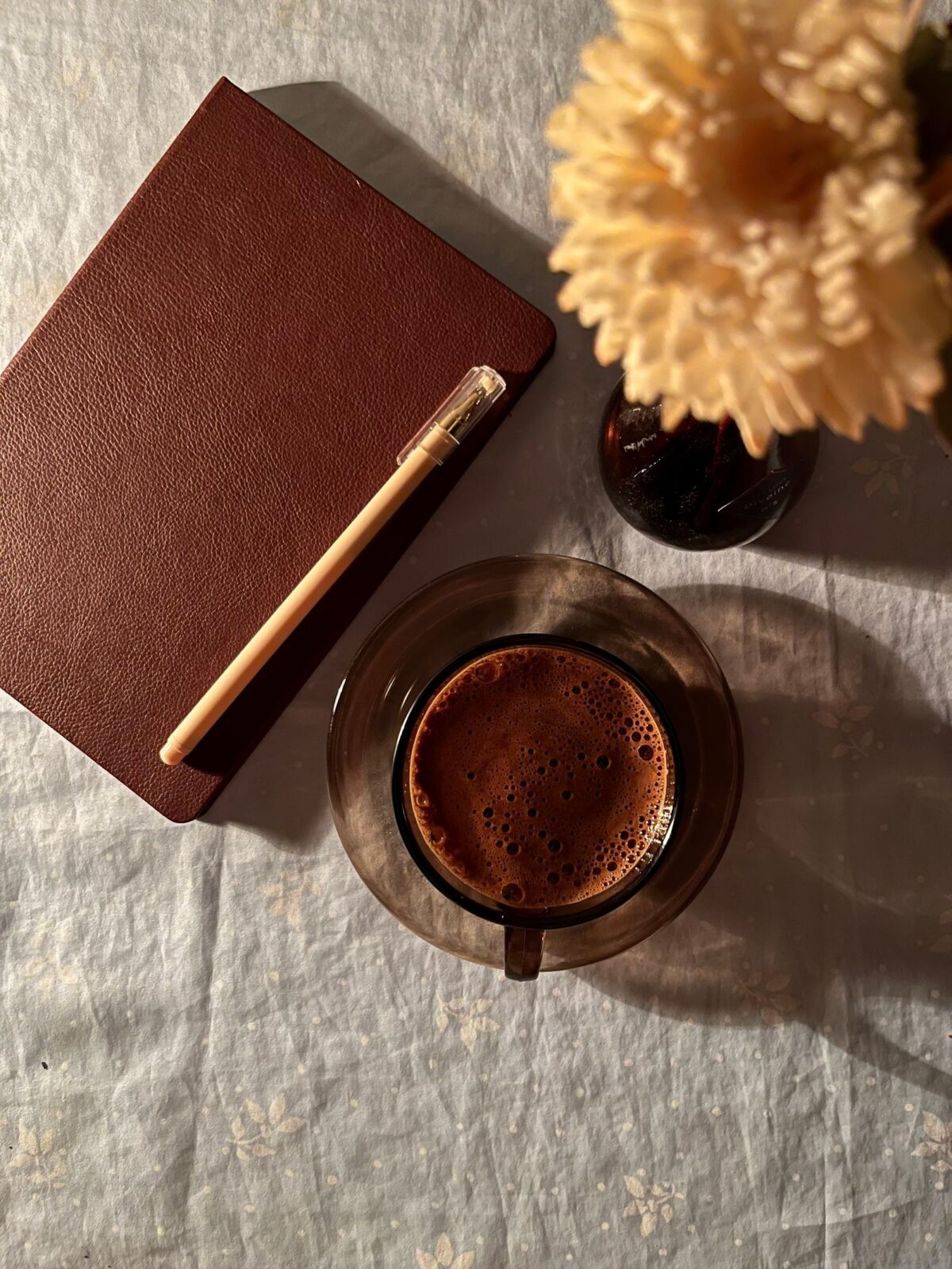 Open journal, coffee cup, and pen arranged in a flat lay on a wooden table