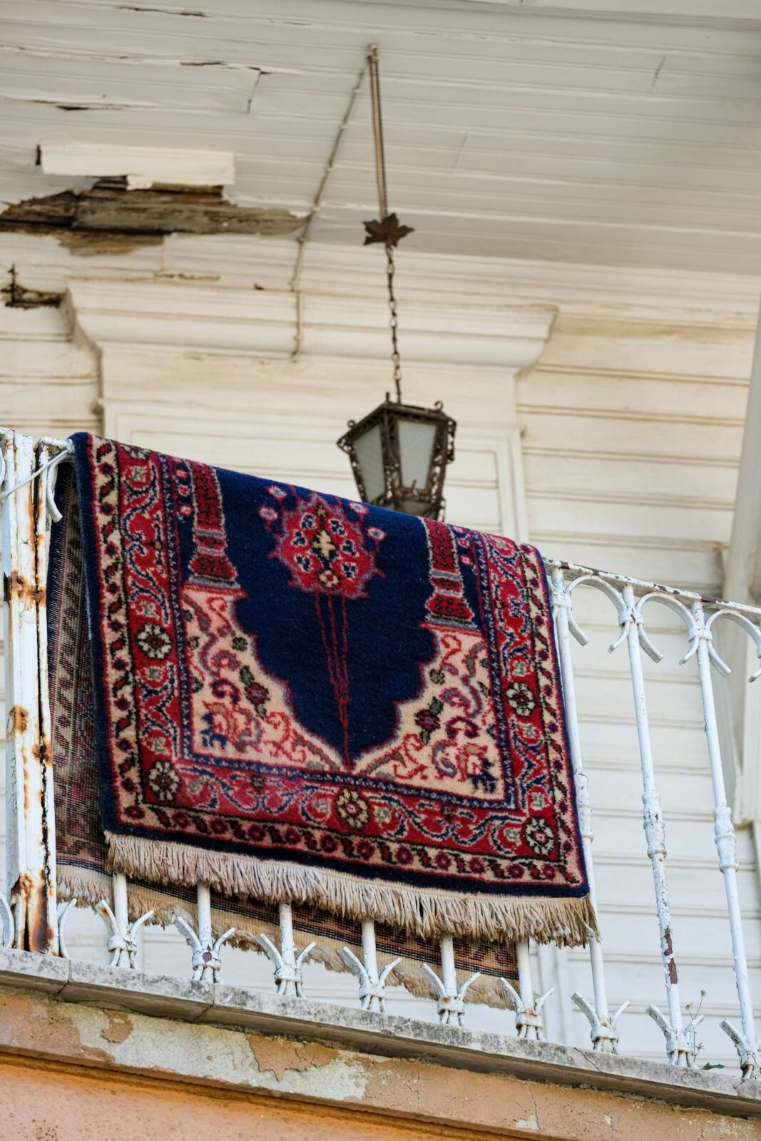 A patterned rug draped over a balcony railing to air out and dry
