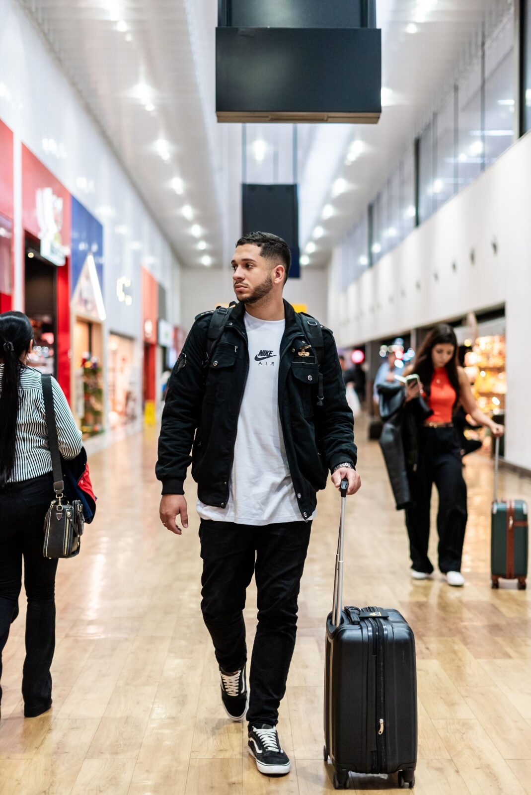 Traveler walking through a modern airport terminal with carry-on luggage