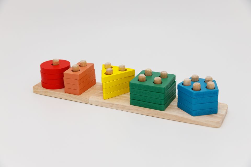 Colorful wooden Montessori-inspired stacking toy with geometric shapes in red, orange, yellow, green, and blue