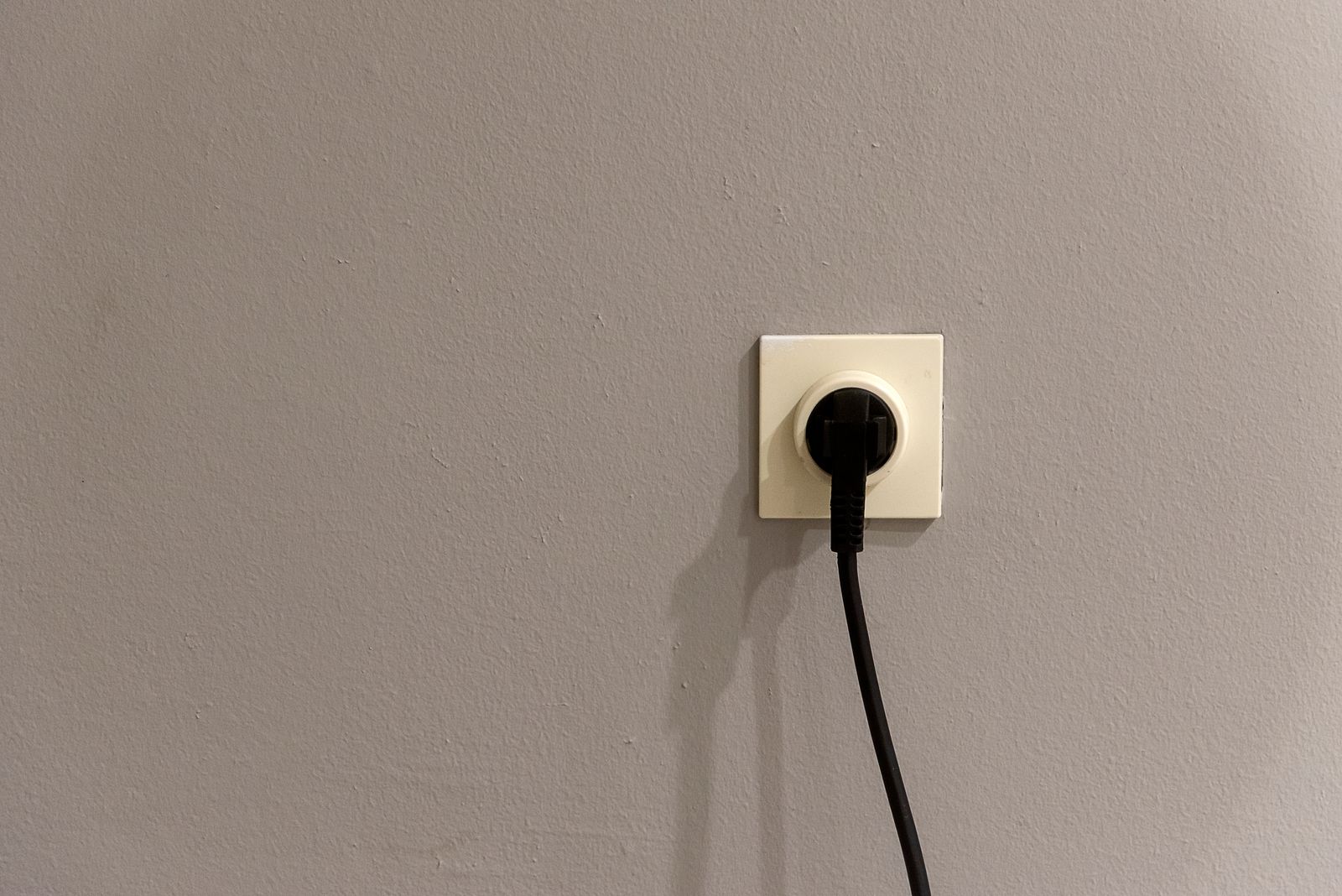 A plain black plug inserted into a wall outlet, representing a smart plug installed in a home