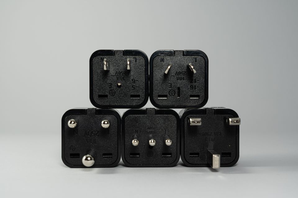 Collection of black international power plug adapters with different prong shapes
