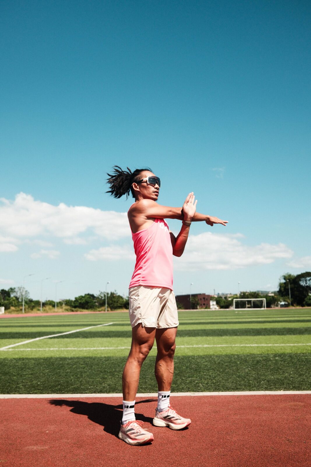 A young athlete stretches on an outdoor running track as part of a post-workout recovery routine