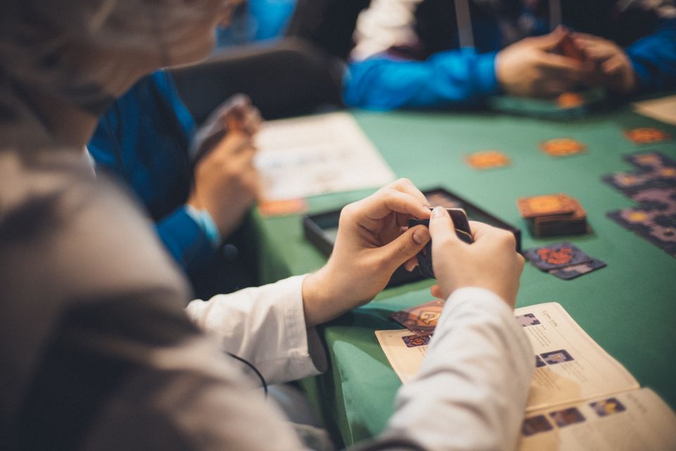 Overhead close-up of several hands holding playing cards around a game table during a group card game
