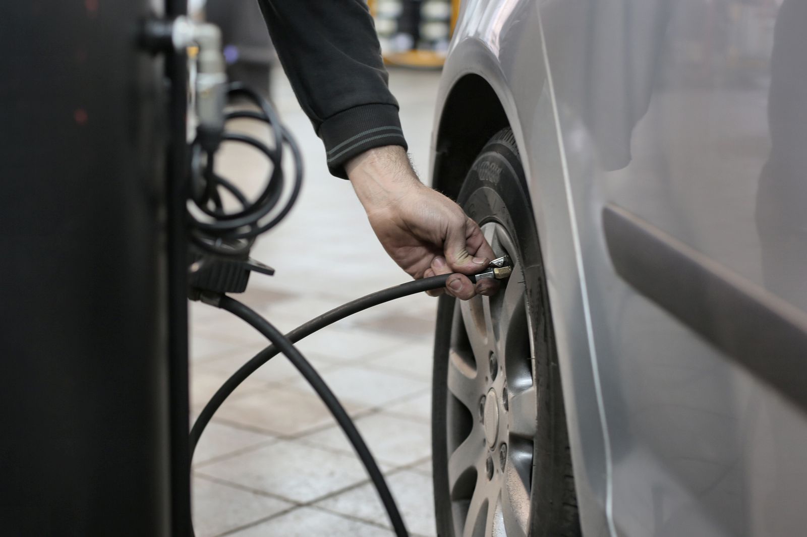 Mechanic using an air hose to inflate a car tire inside a repair shop