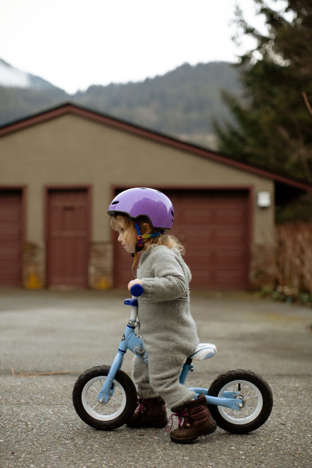 Child riding a balance bike outdoors on a countryside street