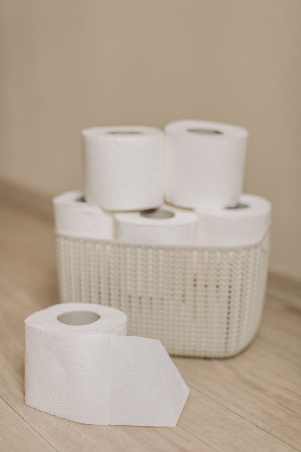 Toilet paper rolls arranged in a woven basket on a wooden floor