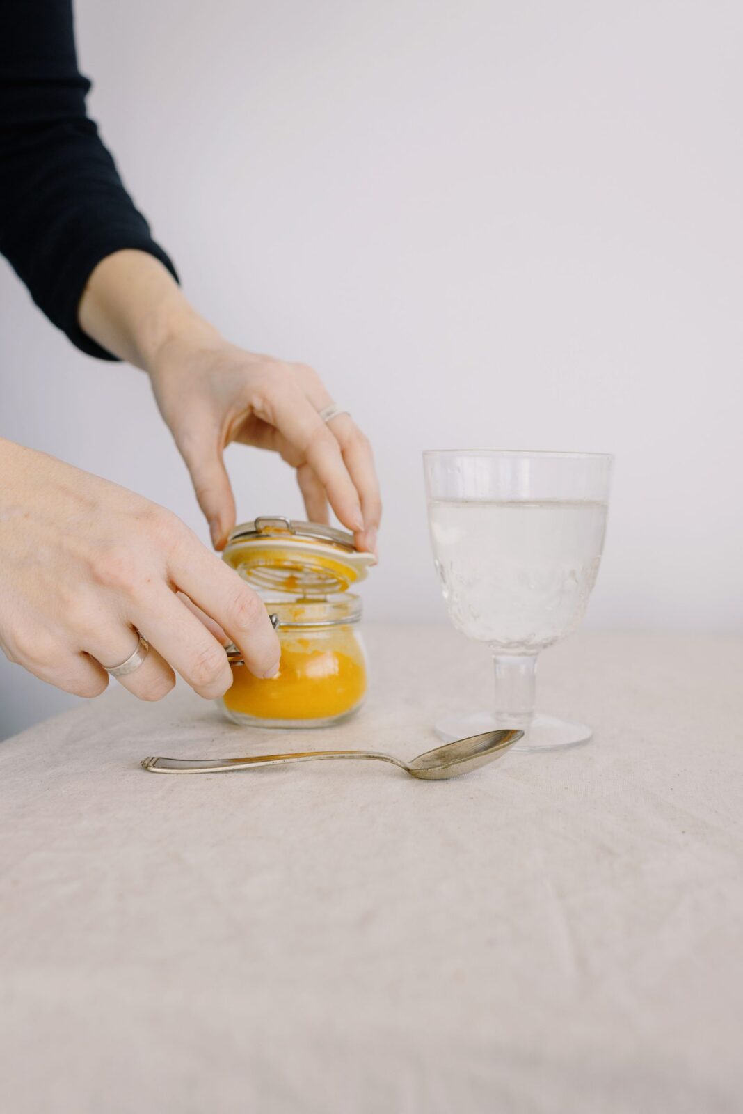 Hands stirring orange fiber powder into a glass of water
