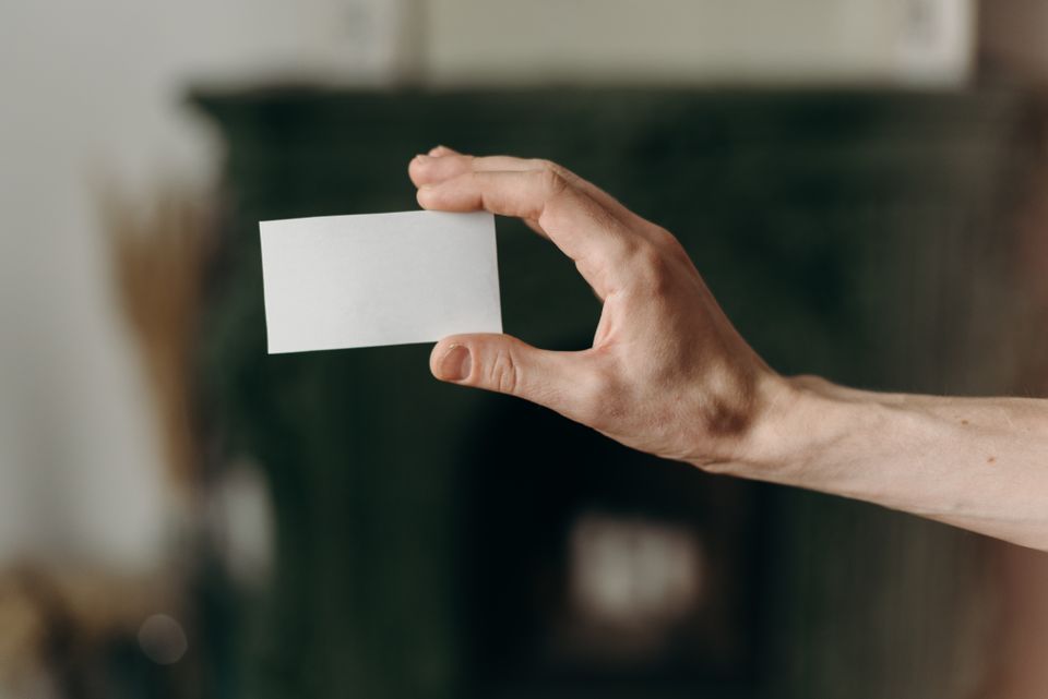 Close-up of a hand holding a single blank card against a dark background