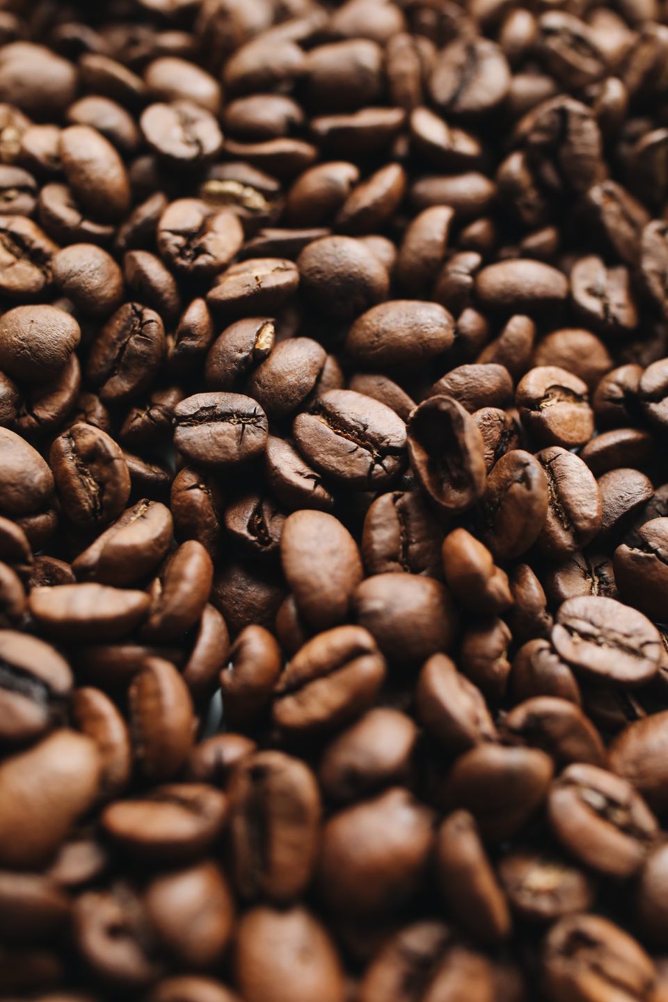 Close-up photograph of dark roasted whole coffee beans showing surface texture