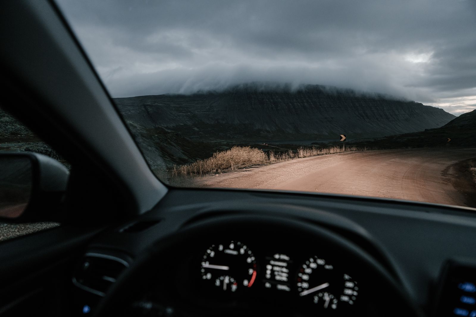 Empty car dashboard and steering wheel viewed from the driver's seat on a mountain road
