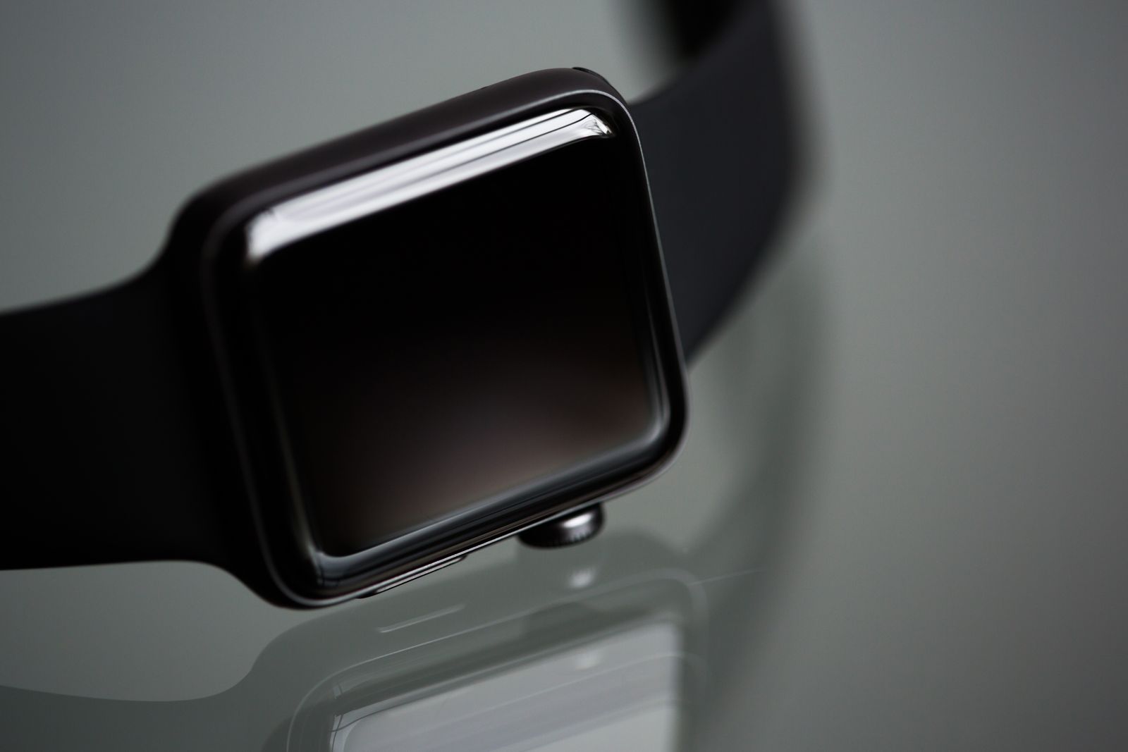 Close-up of a modern smartwatch with a blank black display and dark case resting on a glossy surface