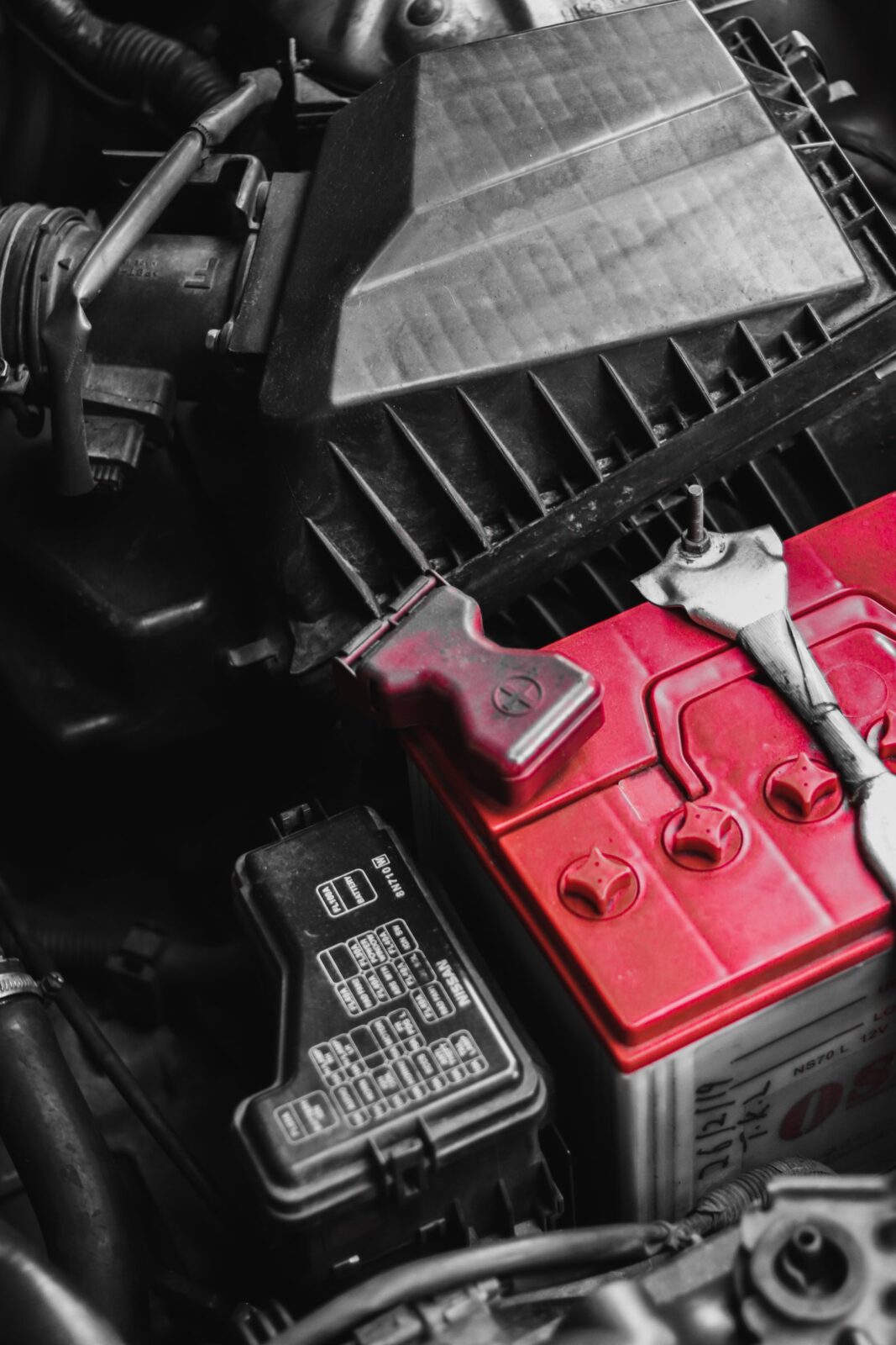 Close-up of a car battery and terminals in an engine bay, the kind of battery a maintainer keeps topped off during storage