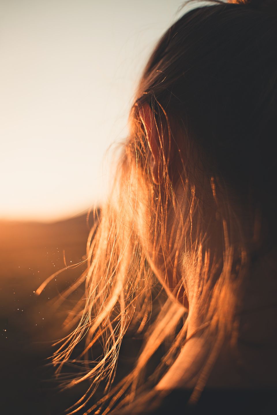 Close-up of a woman's hair strands glowing in warm golden-hour sunlight
