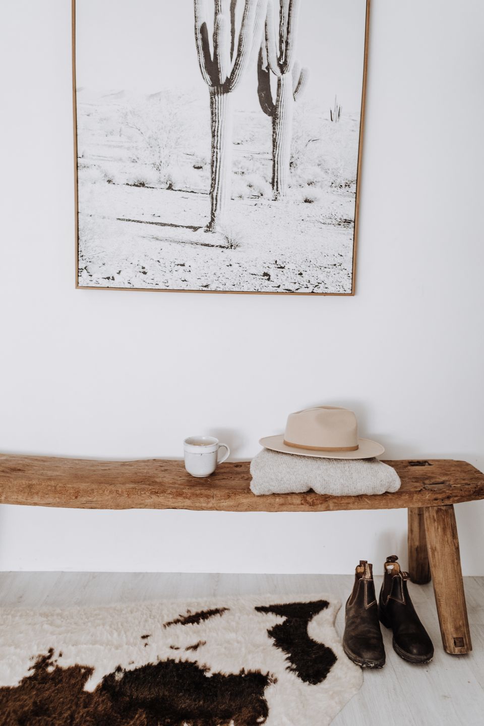 Wooden entryway storage bench styled with boots and a folded sweater in a bright mudroom corner