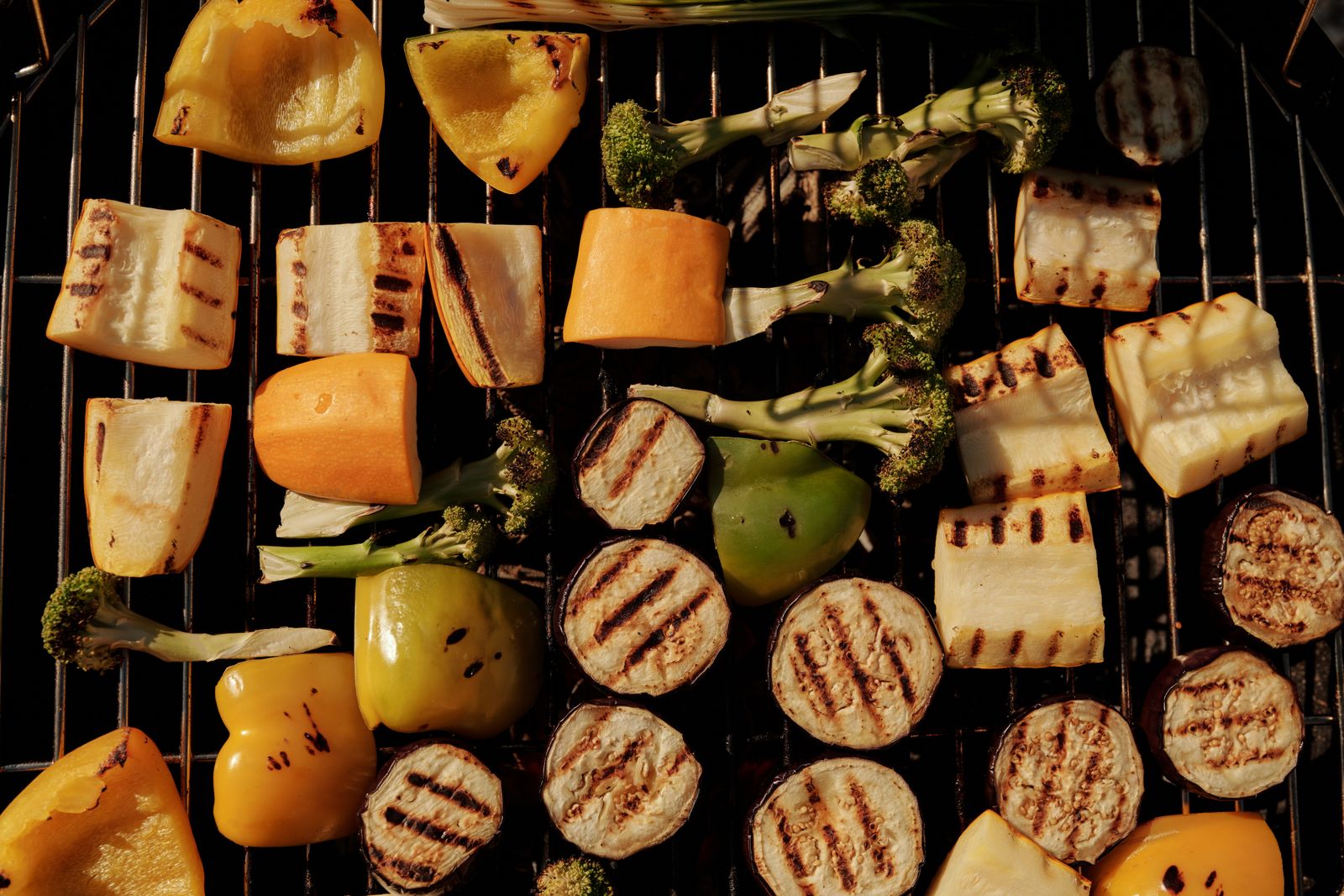Bell peppers, zucchini, and eggplant grilling on a wire grate