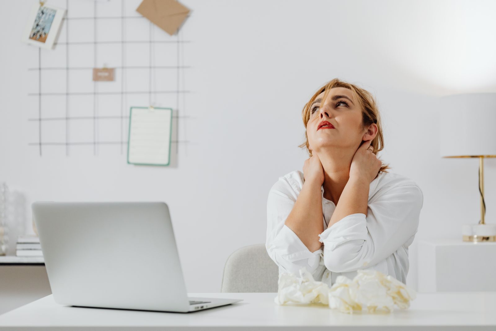 Person at a laptop rubbing the back of their neck at a desk