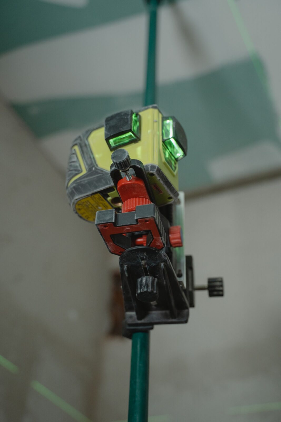 Green laser level mounted on a tripod projecting bright green lines indoors