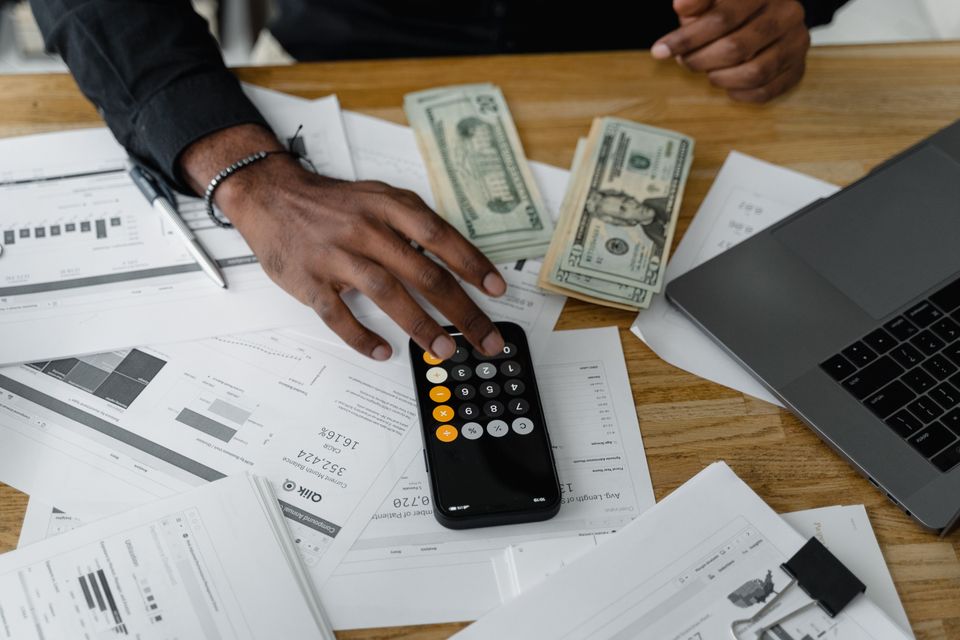 Calculator, cash, and laptop laid out on a desk for financial planning