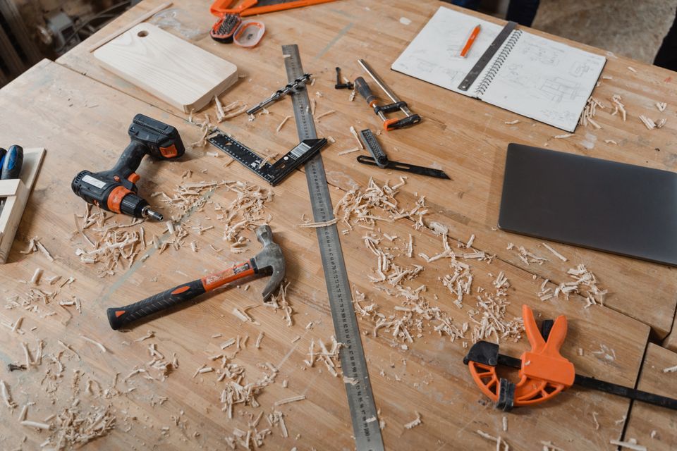 Various hand tools, sketches, and wood shavings arranged on a workbench