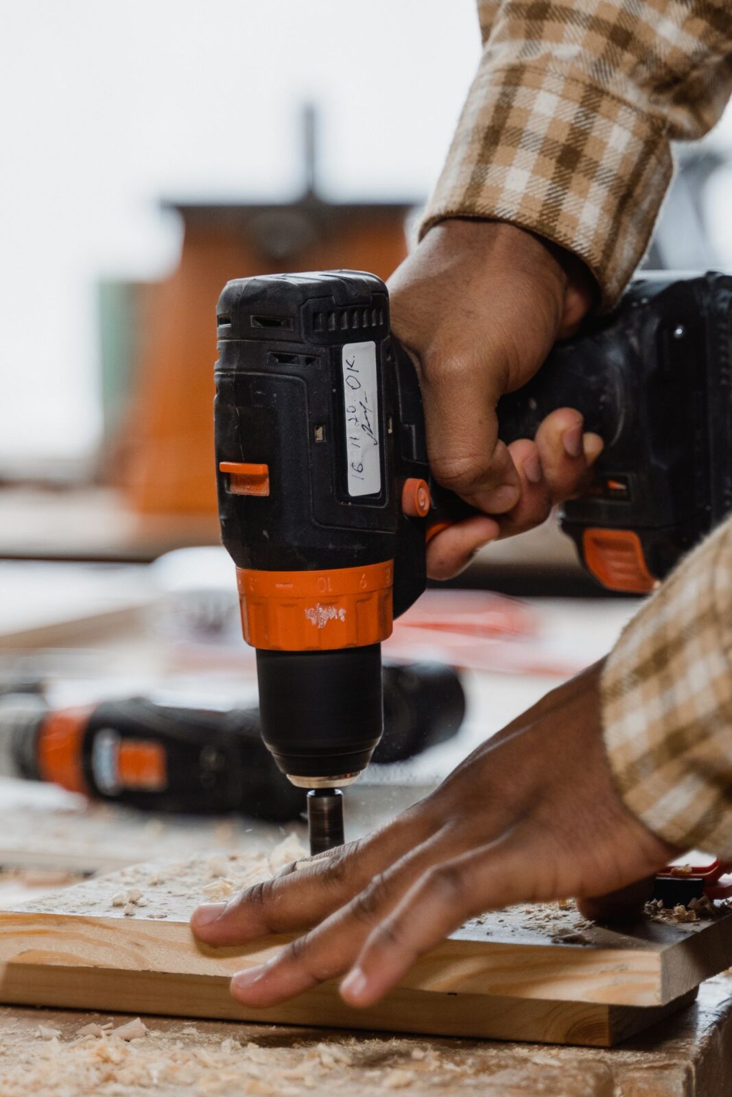 Close-up of a person using a cordless power drill on a wood workbench