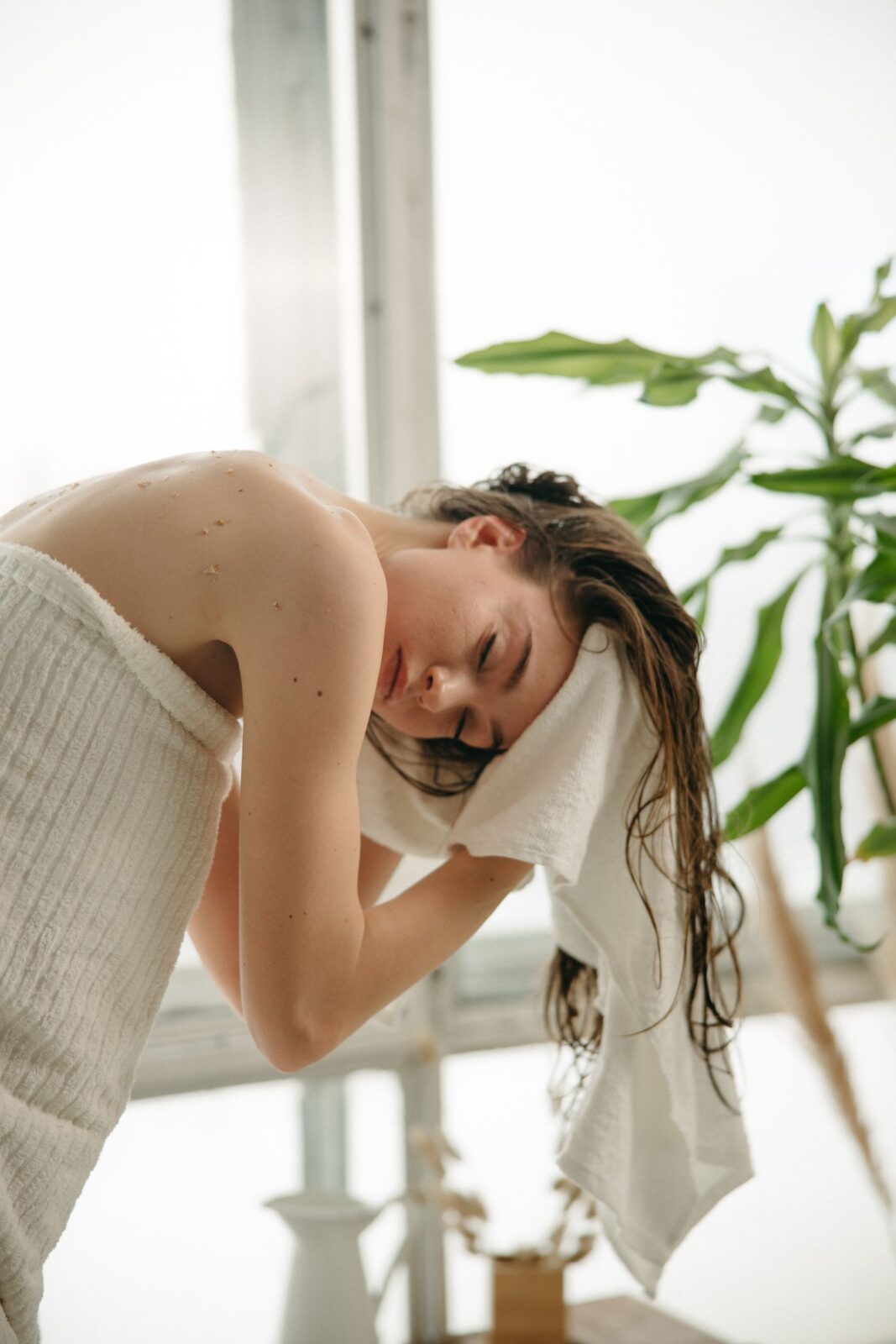 Woman in a towel gently drying and wrapping her wet wavy hair, a step often used before diffusing