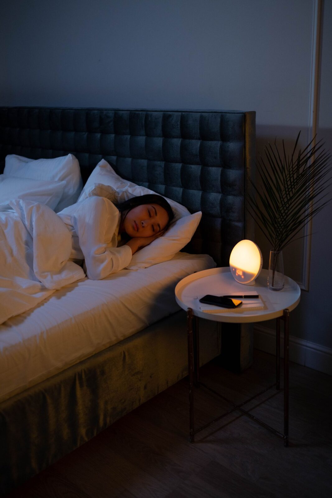 A woman sleeping peacefully in a dimly lit bedroom, the time window most wearables use to capture overnight heart rate variability