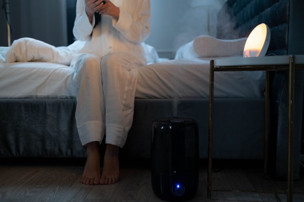 A humidifier releasing soft mist in a dim, cozy bedroom at night