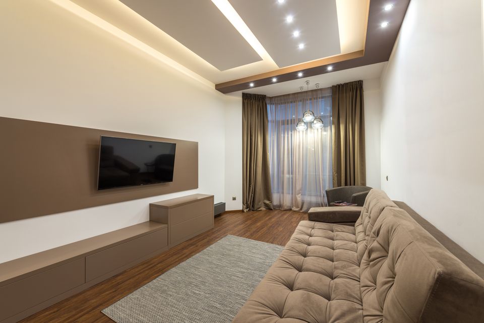 Spacious living room with a wall-mounted television, beige sofa, and warm lighting