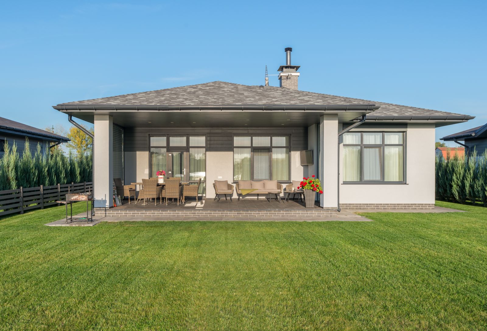 A contemporary house exterior with a large, evenly green backyard lawn