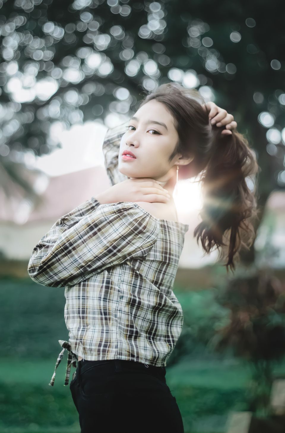 Close-up of a woman holding a section of her hair, backlit by soft sunlight