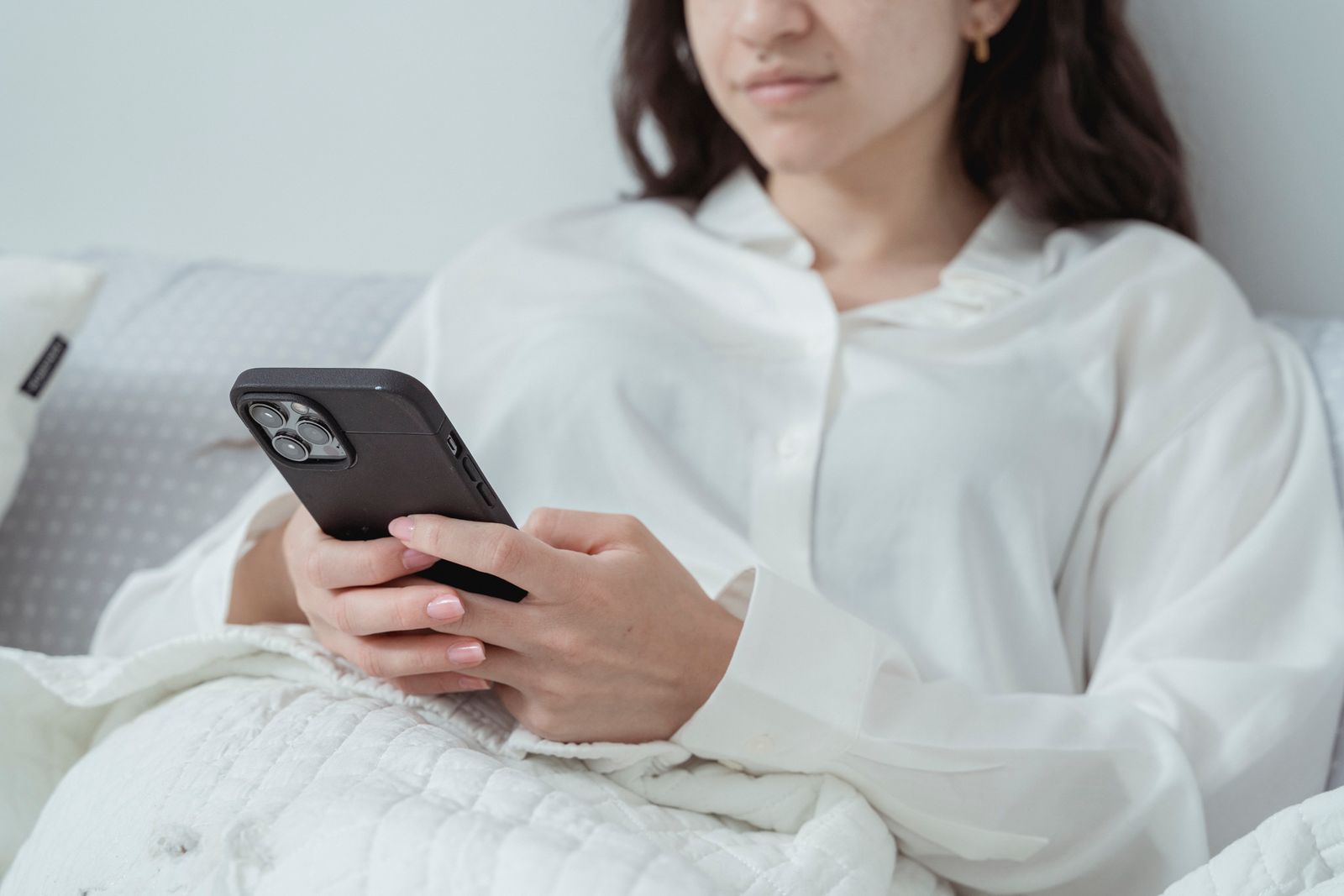 A woman relaxing in bed in the morning while checking her phone