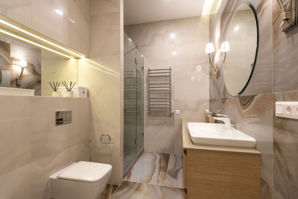 Modern bathroom with a wall-hung toilet, marble-look tile, and wood vanity