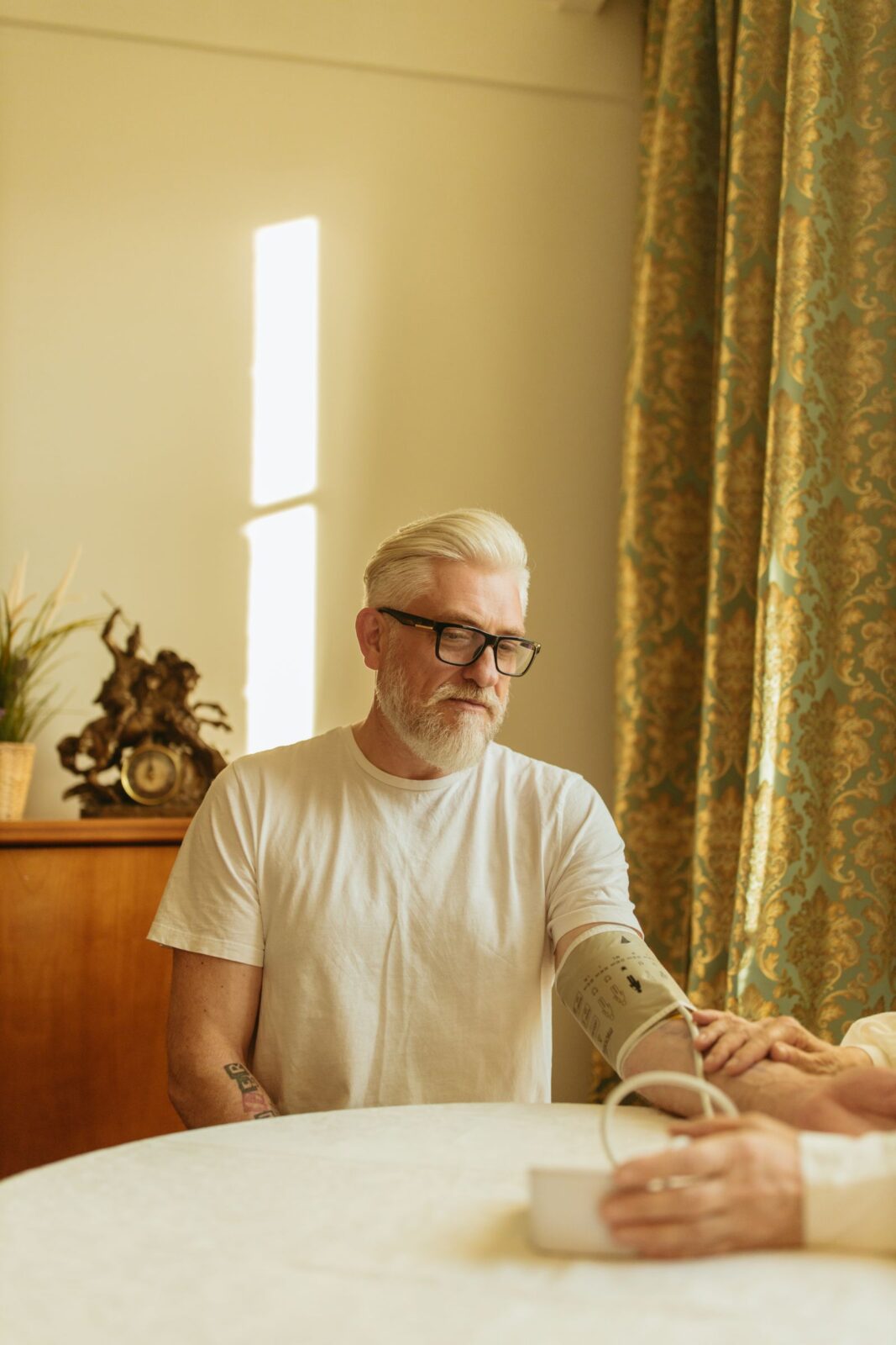 A healthcare provider measuring an older man's blood pressure with a traditional cuff