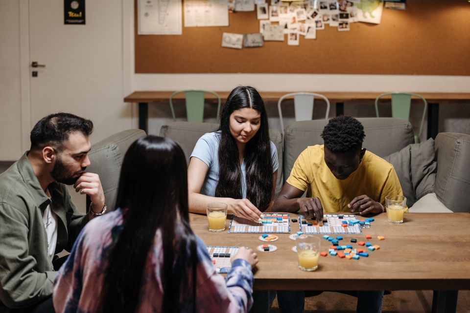 A group of family members sitting around a wooden table together while playing a board game